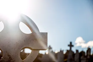 Sonnenlicht auf Grabkreuz.