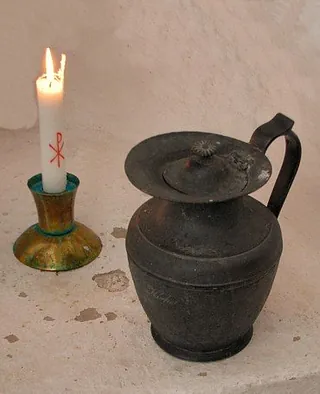 Kerze und Kanne auf Stein.