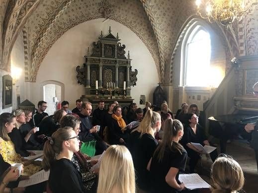 Chor probt in einer Kirche mit bemalter Decke.