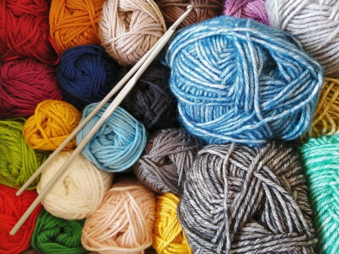 Bunte Wollknäuel und Stricknadeln.